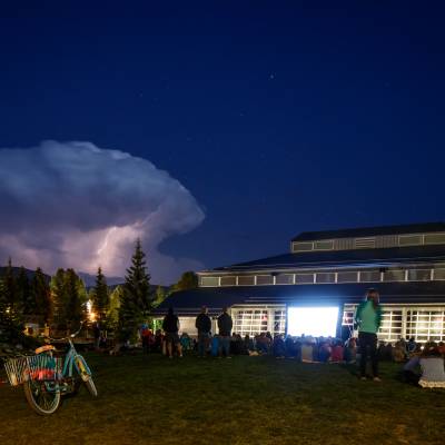 The exterior of the Riverwalk Center in Breckenridge at night with a thunderstorm on the horizon