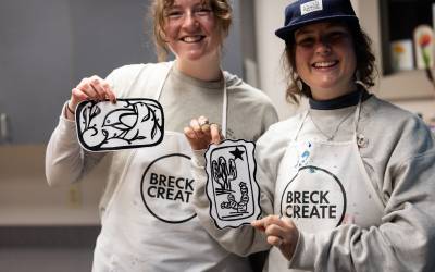 Two Lino-cut printing class students proudly show off their prints.