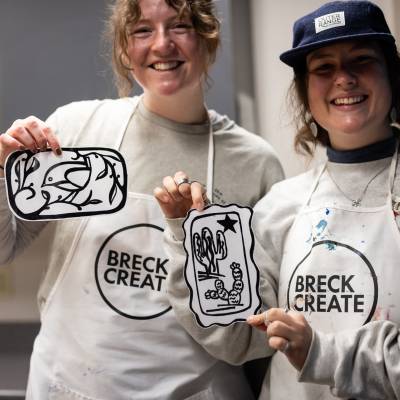 Two Lino-cut printing class students proudly show off their prints.