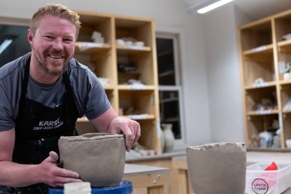 A clay hand-building class participant smiles with his large vase