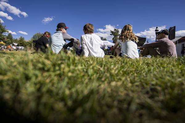 Breckenridge locals sit in the grass while enjoying live music at an AirStage Aprés event