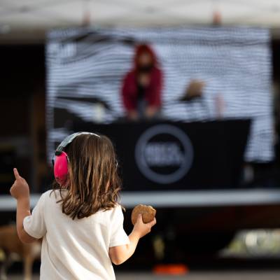Little girl dancing to a DJ with a cookie in her hand at the Airstage Apres event at BIFA 2023