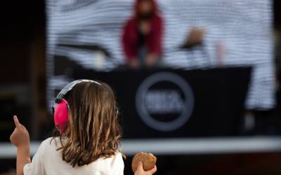 Little girl dancing to a DJ with a cookie in her hand at the Airstage Apres event at BIFA 2023