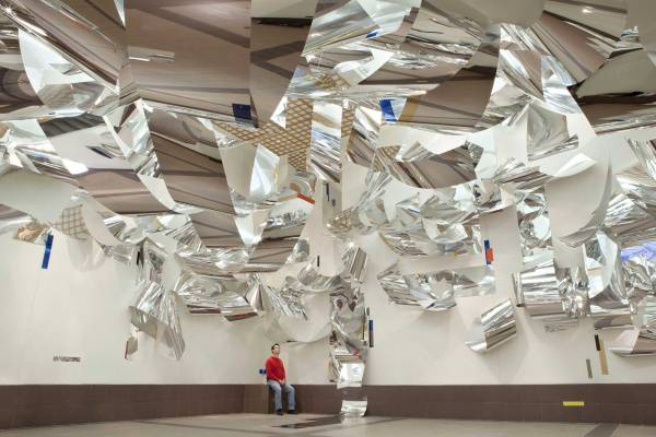 Abstract installation by artist Sharon Louden featuring reflective panels hanging and undulating from the ceiling and walls.