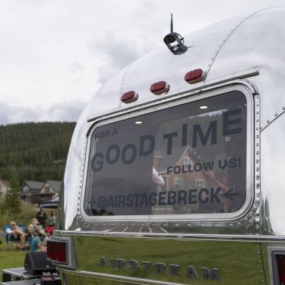 The AirStage, an Airstream trailer retrofitted into a mobile stage is featured at a neighborhood block party. The back window says, "for a good time, follow us @airstagebreck."