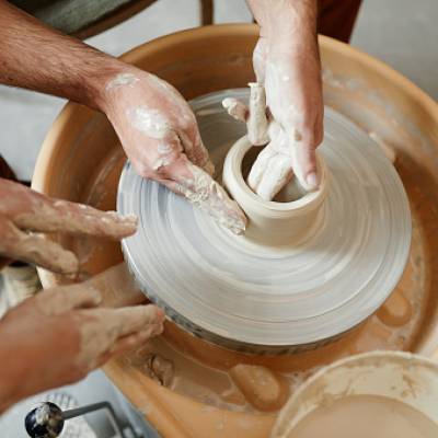 Instructor guiding on pottery wheel